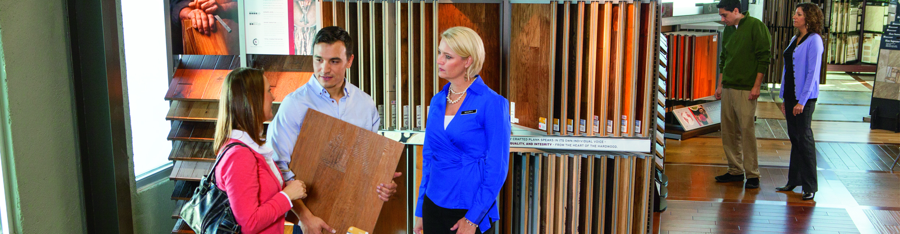 Salesperson helping people shopping for hardwood flooring .