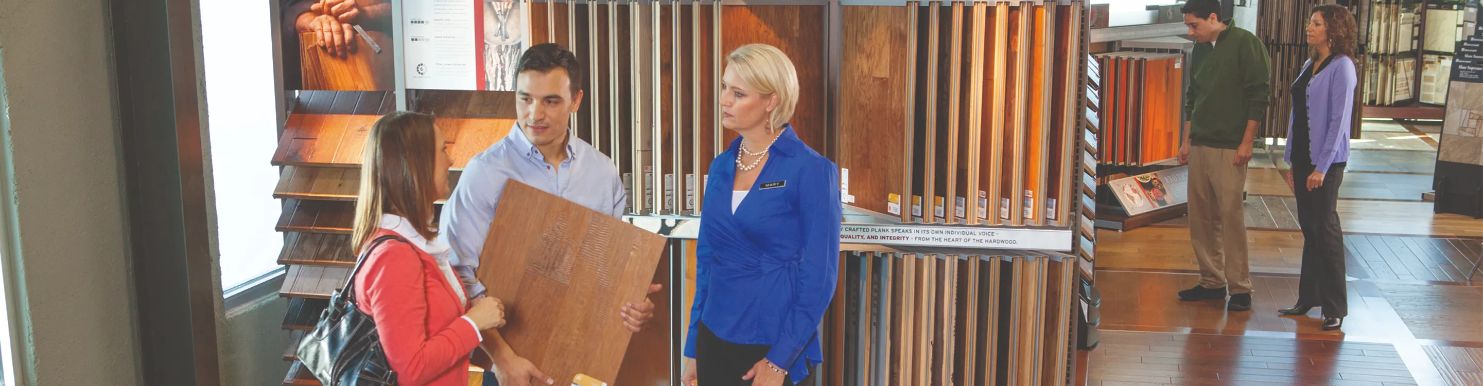 Salesperson helping people shopping for hardwood flooring .