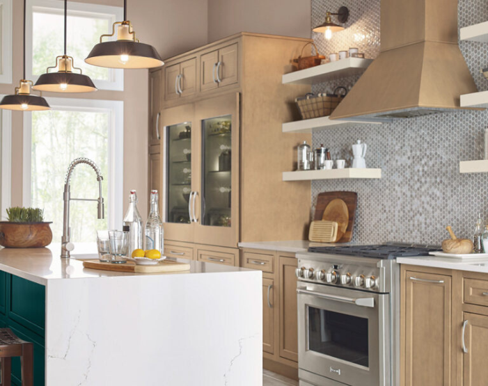 A modern kitchen with dark cabinetry, brass hardware, and a sleek black countertop. A stainless steel appliance and a wooden shelf with decorative items add warmth and texture to the space.